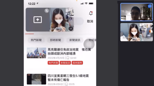Video call on smartphone showing two participants, one wearing a mask and browsing news on screen.