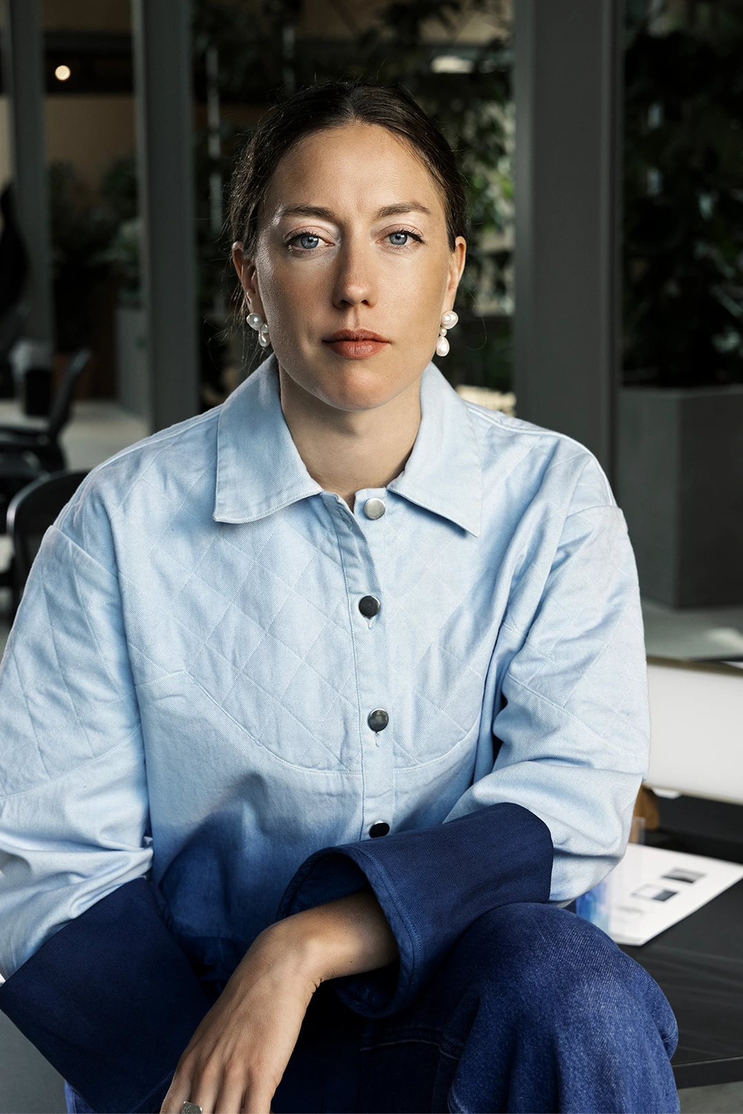 Marjan V.A with pearl earrings wearing a blue dial-tone jacket sitting indoors.