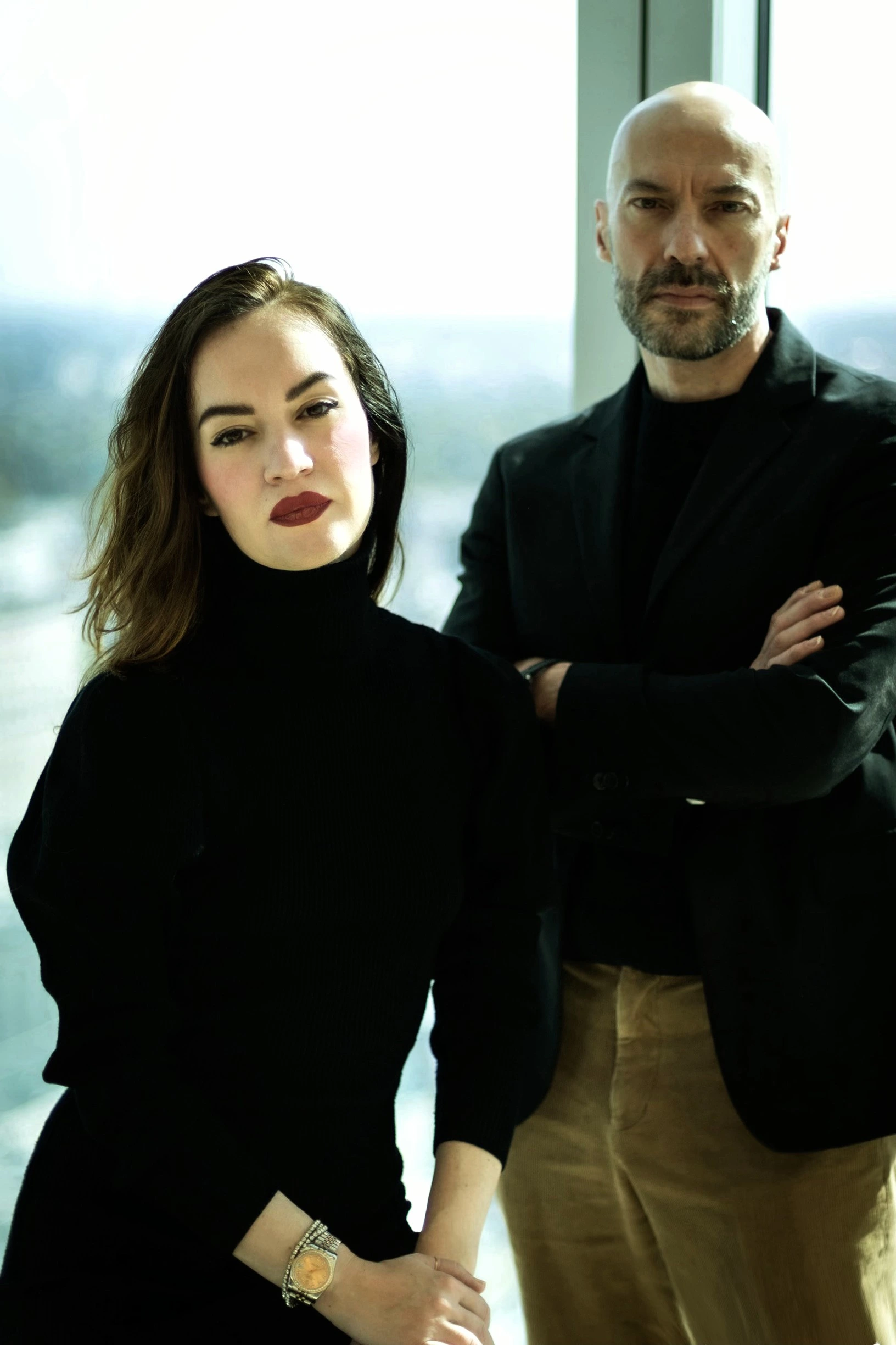 Auronda Scalera & Alfredo Cramerotti stand confidently in front of a bright window.