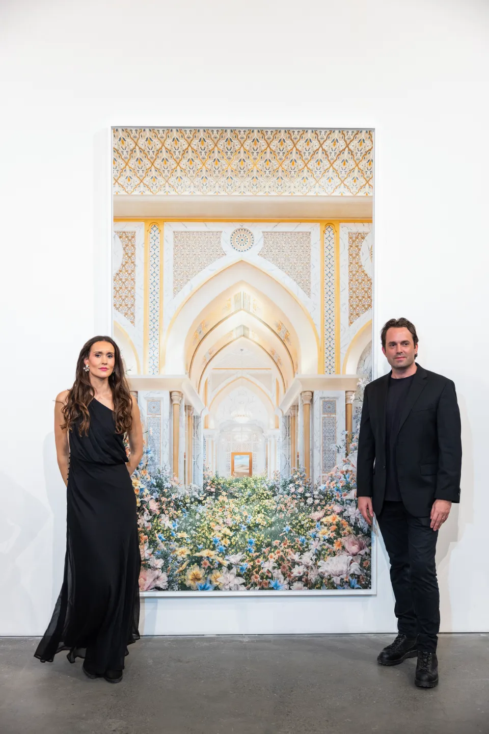 Ryan i Wexell in black stand beside a large, ornate floral and archway painting in a gallery.