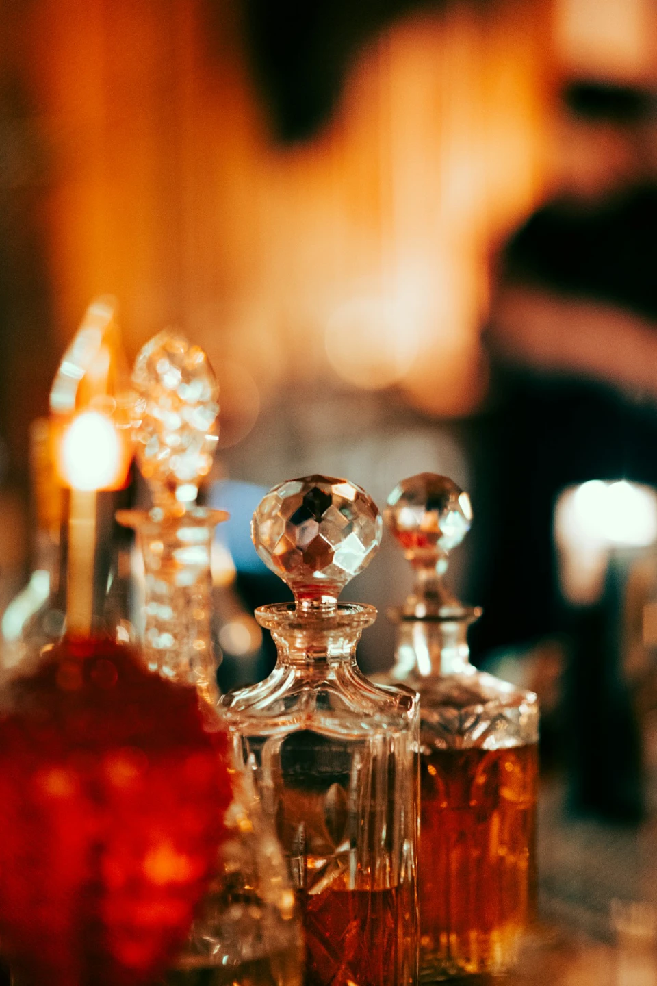 Crystal decanters filled with amber liquid, lit by warm, blurred background lighting.