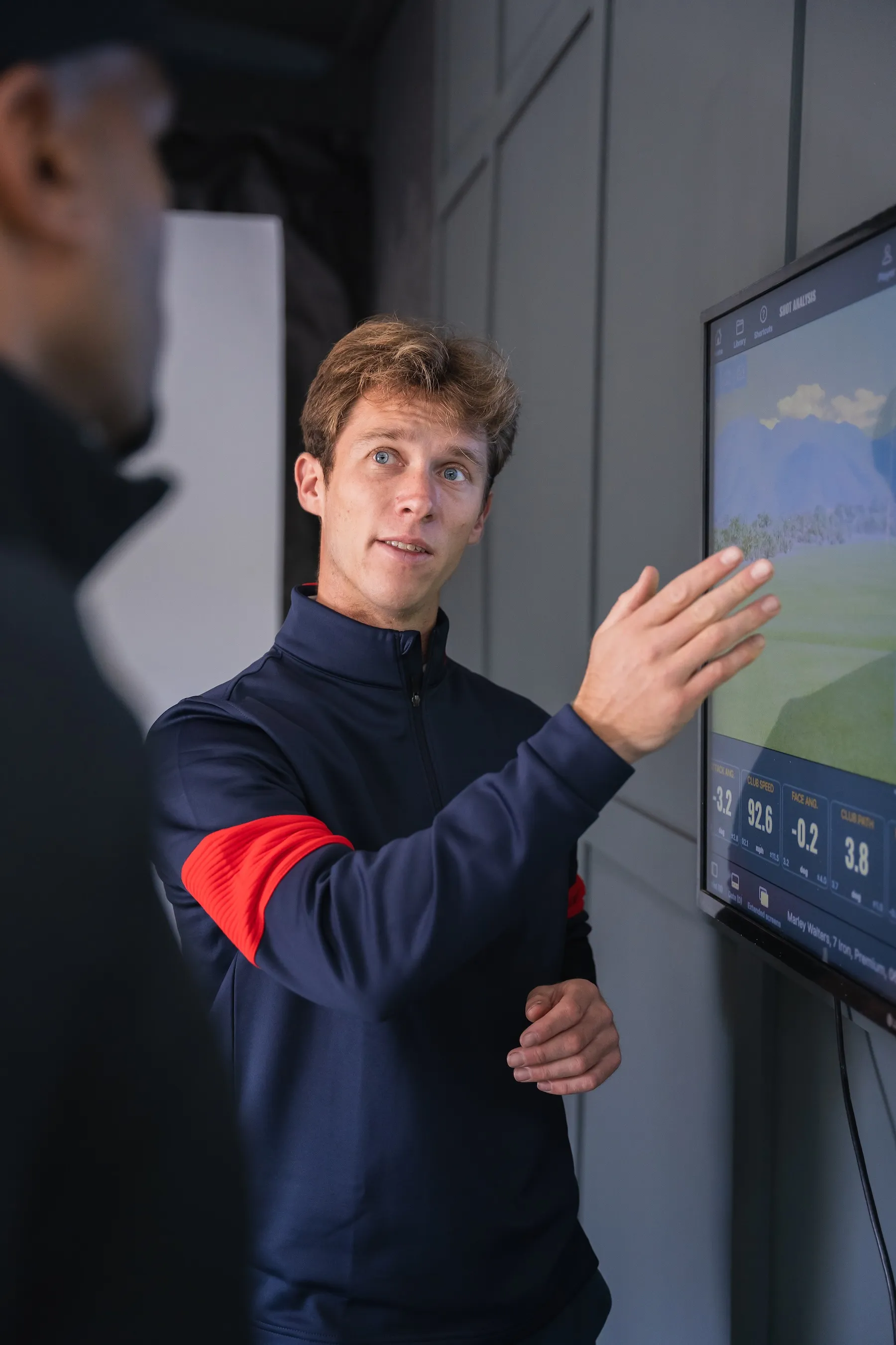 Golf coach explaining TrackMan swing data on a screen during monthly golf coaching in Derby