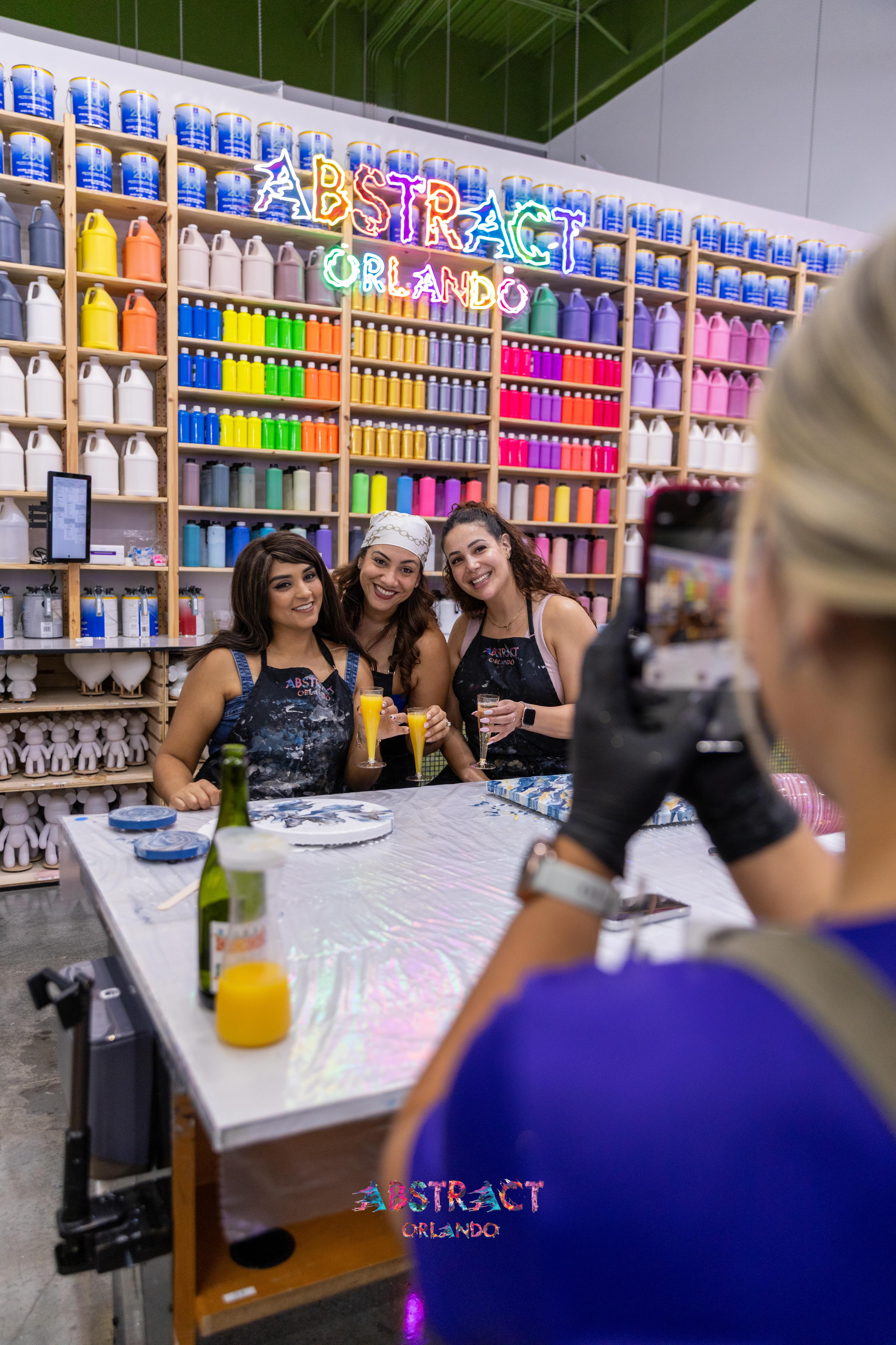 Friends toasting mimosas at their painting table
