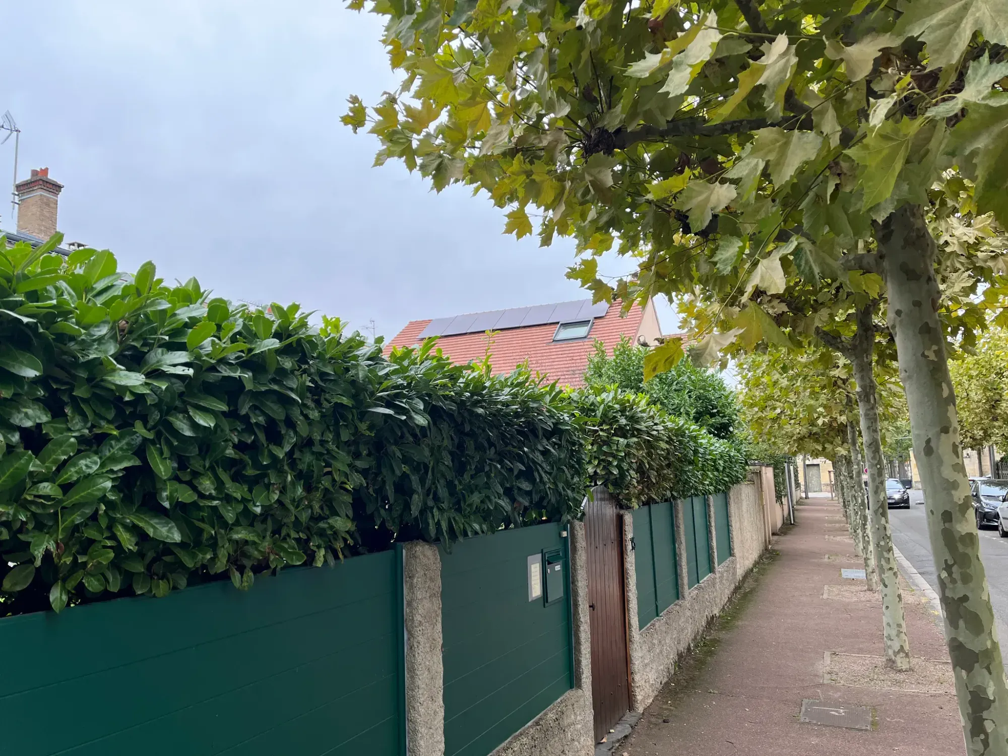La maison vue depuis la rue, l'installation discrète derrière la haie, à Maisons-Laffitte (78600)