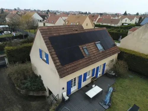 Vue aérienne de la maison et des seize modules sur la toiture en tuiles béton, à Osny (95520)