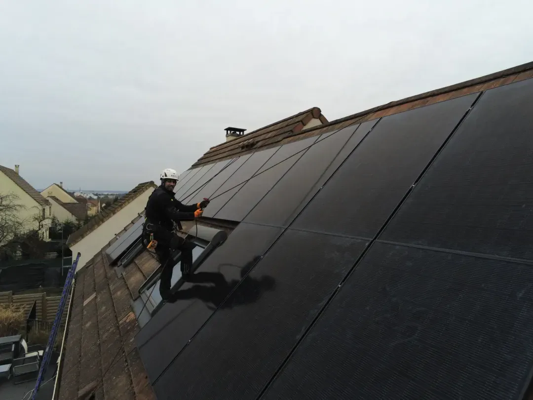 Pose des modules en cours, technicien sécurisé sur la toiture, à Osny (95520)