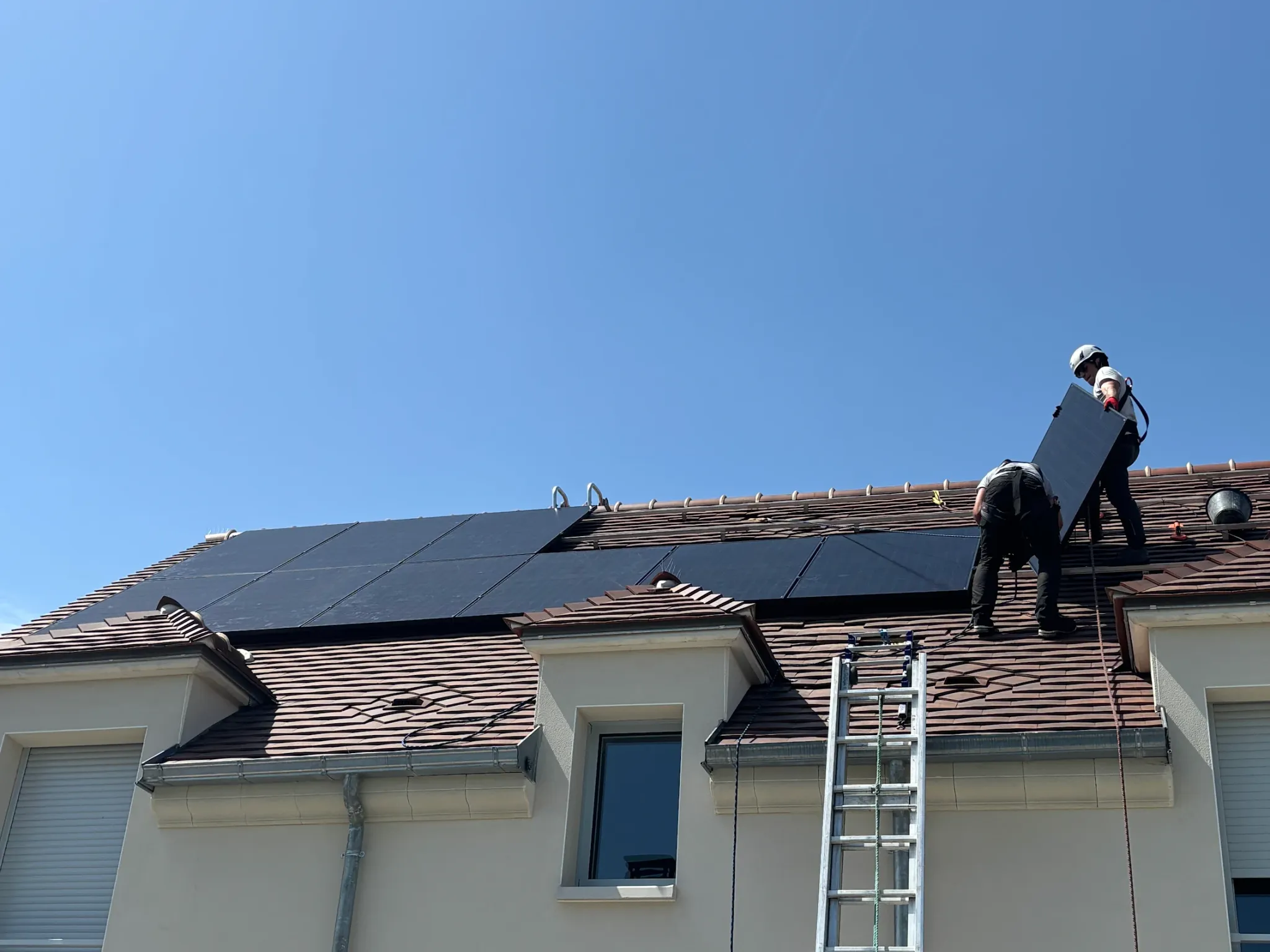 Deux techniciens Volt posent un module sur le toit, en pleine vague de chaleur, à Bussy-Saint-Martin (77600)