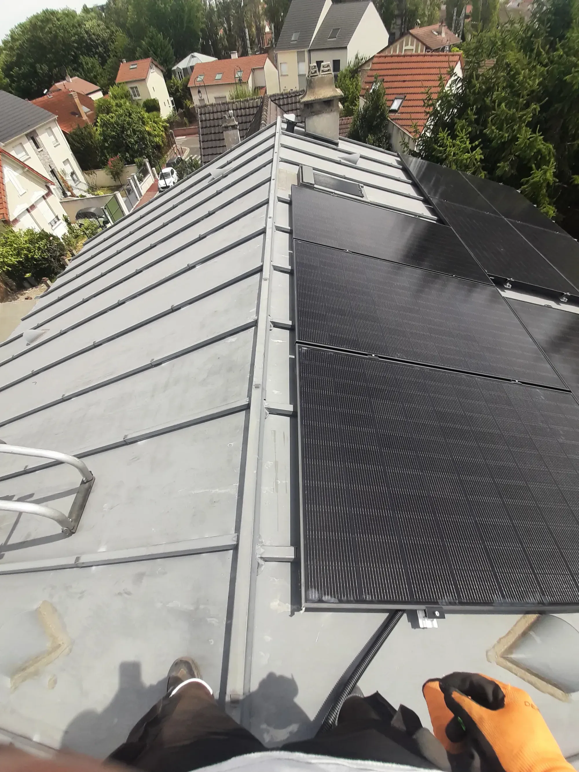 Pose des modules photovoltaïques sur la toiture en zinc à tasseaux, un technicien Volt sur le toit, à Antony (92)