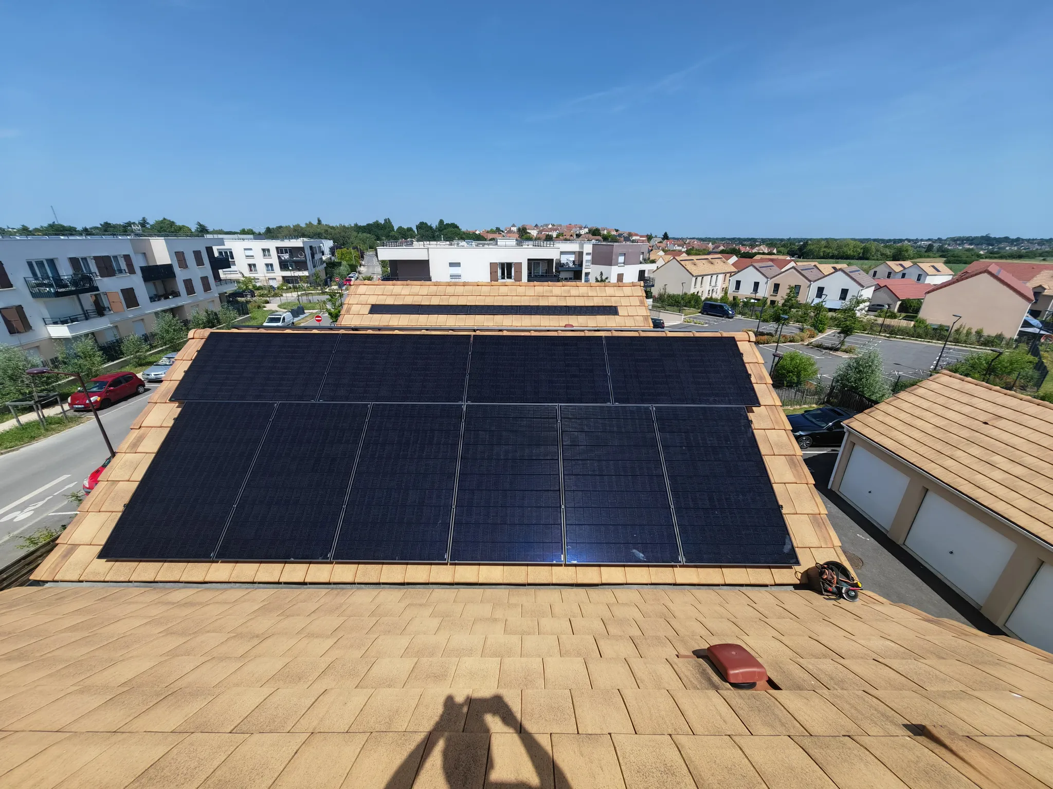 Vue d'ensemble des modules photovoltaïques noirs sur la toiture en tuiles mécaniques, à Montlhéry (91)
