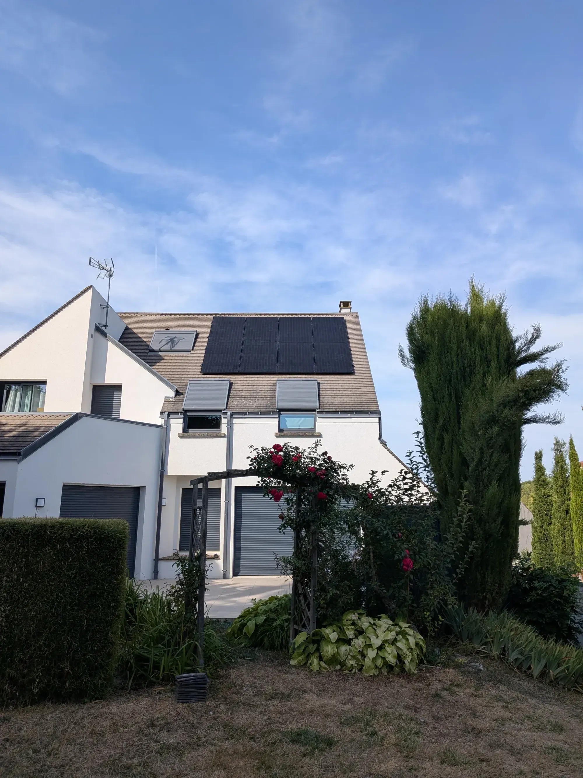 La maison vue du jardin, avec ses huit modules photovoltaïques sur la toiture en tuiles plates, à Nanteuil-lès-Meaux (77)