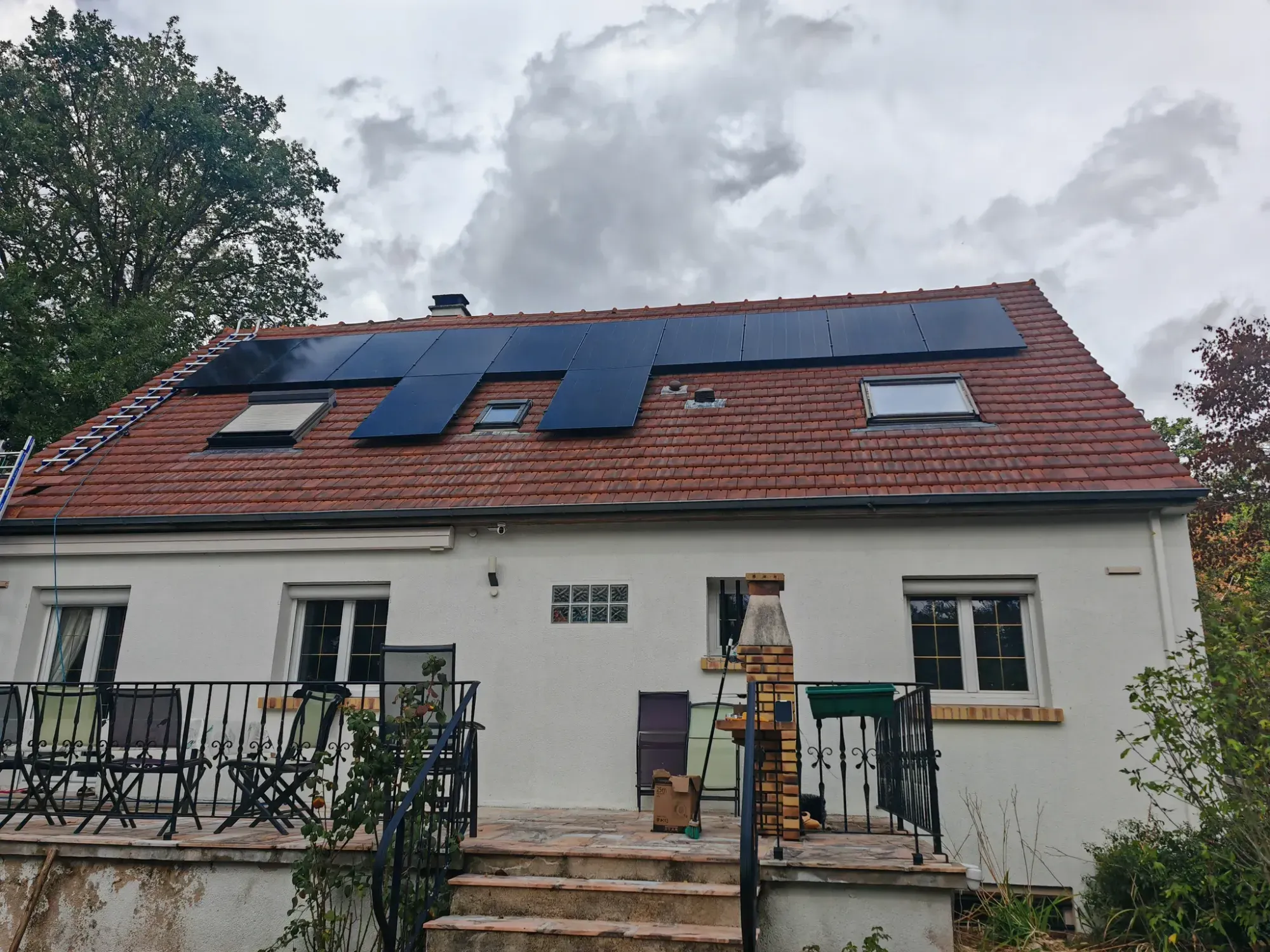 La maison et ses douze modules autour des fenêtres de toit, sur la toiture en tuiles mécaniques anciennes, à Boissettes (77)
