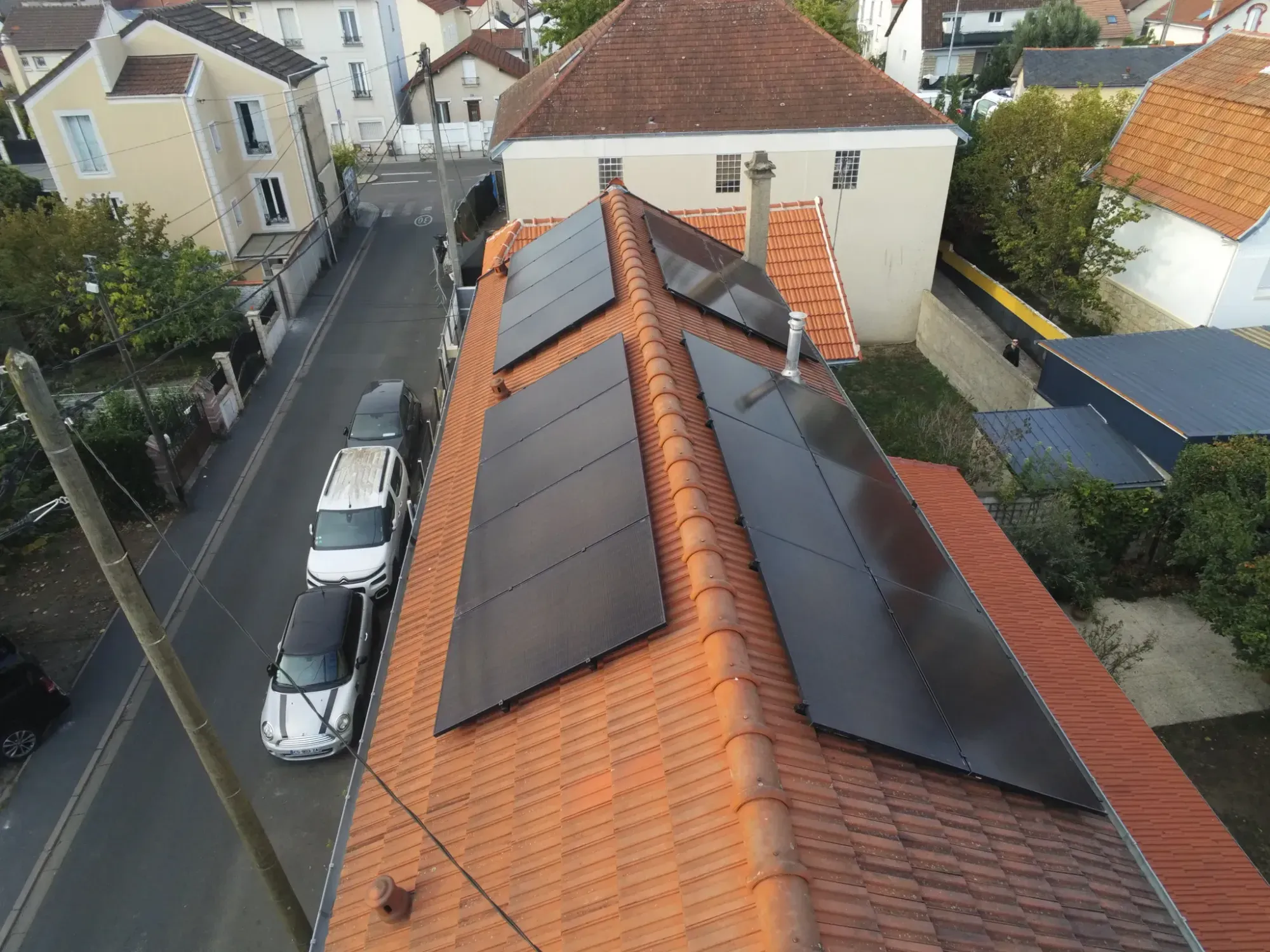 Les modules photovoltaïques sur les deux pans de la toiture en tuiles mécaniques, vus du ciel, à Houilles (78)