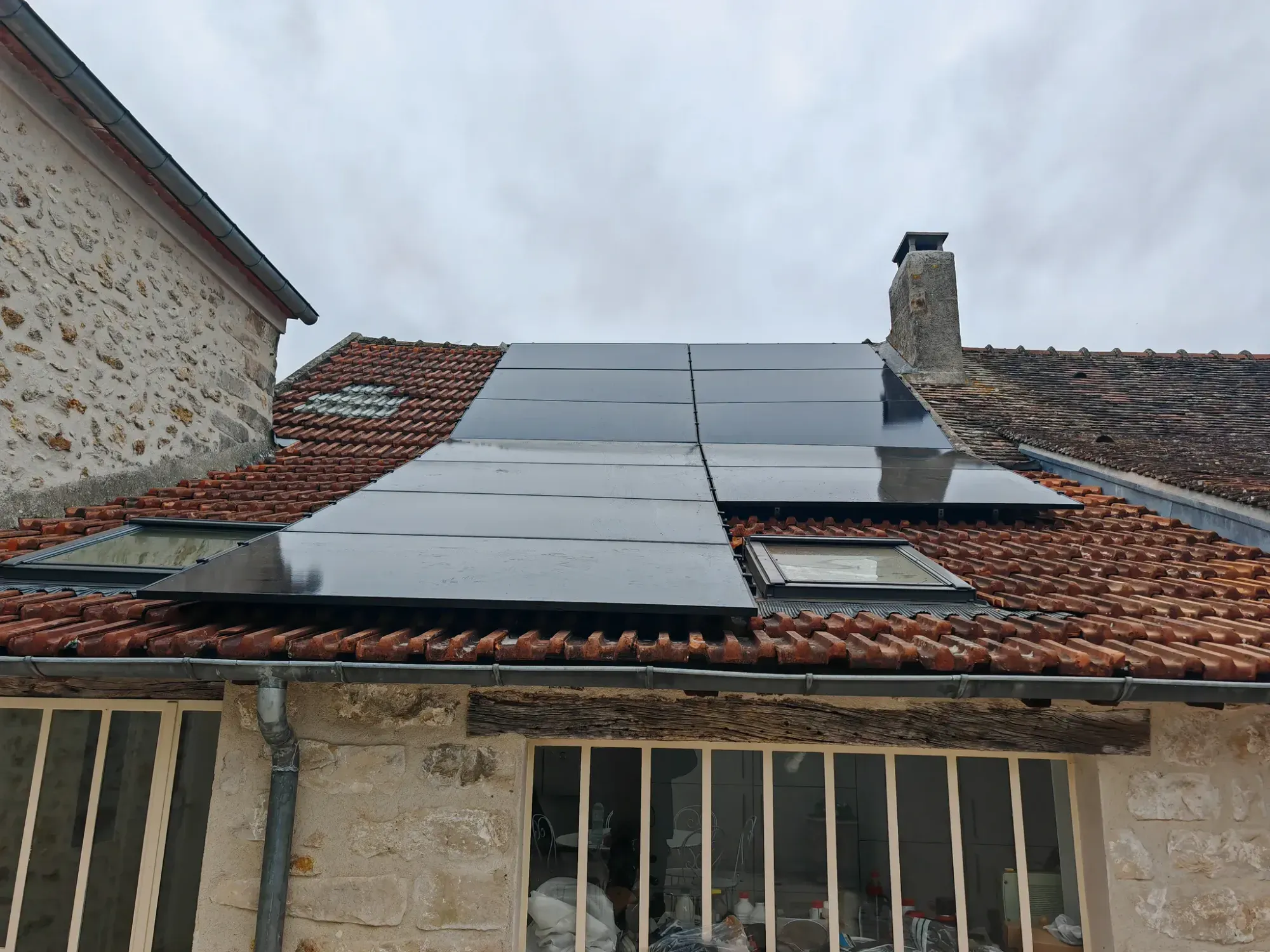 La maison en pierre vue de la cour, avec ses douze modules sur le pan à deux inclinaisons, à Perthes (77)