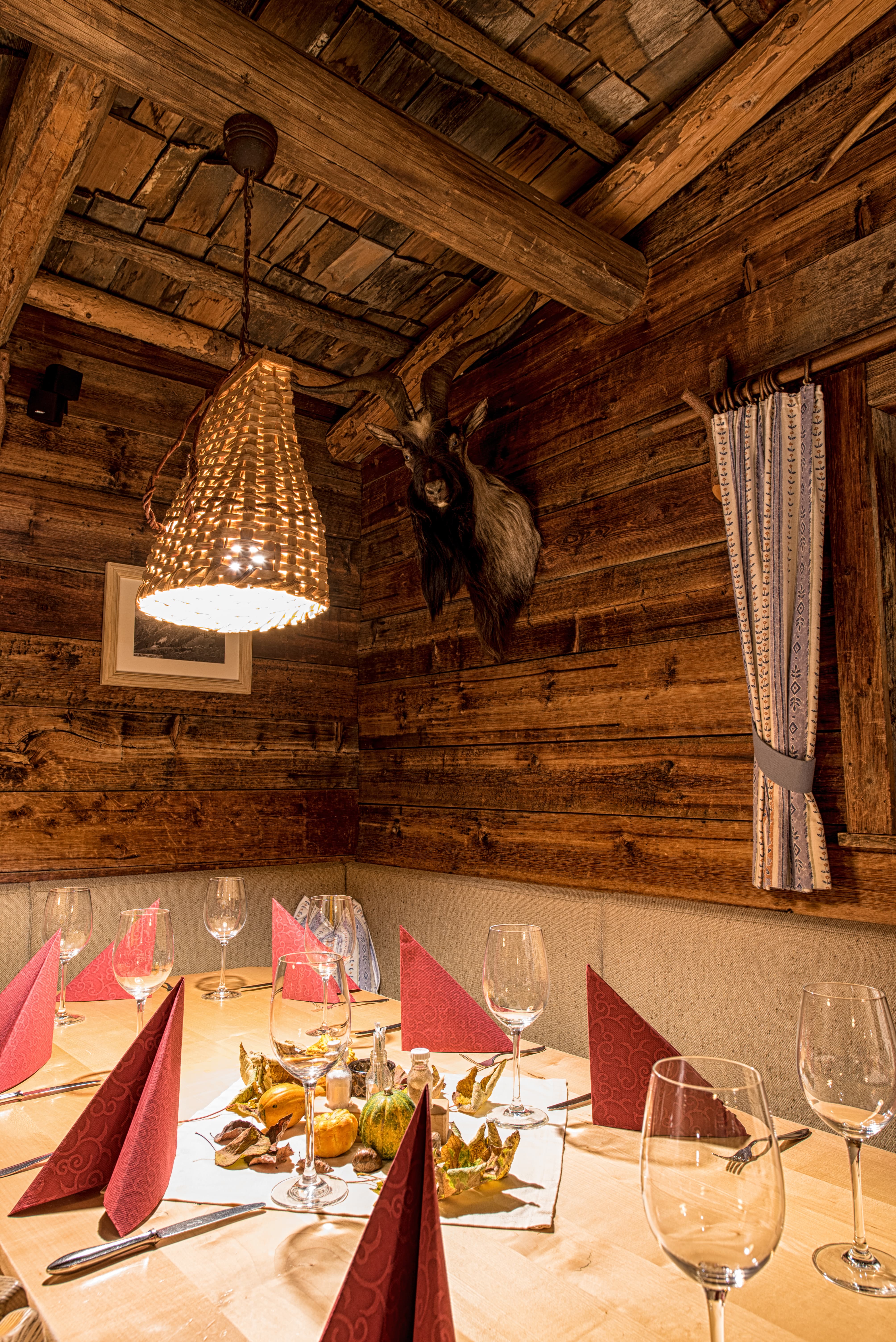 Rustikaler Holzesstisch mit roten Servietten und dekorativen Kürbissen in einer Hütte.
