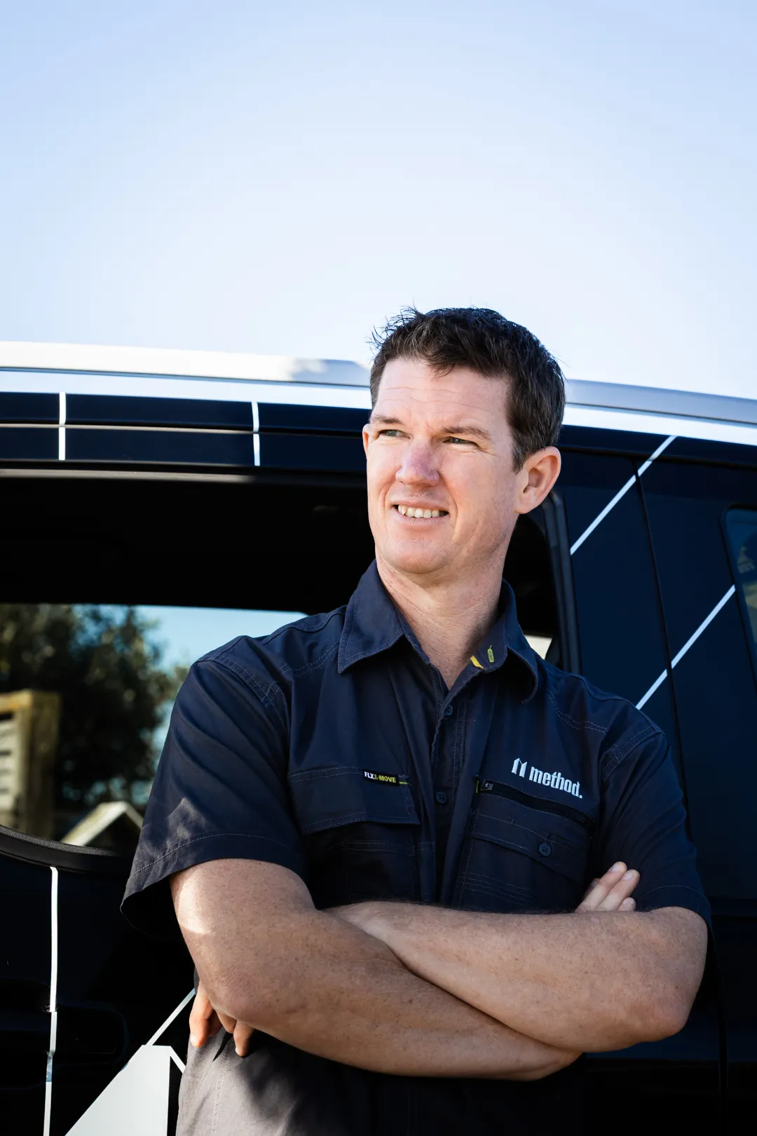 A Method Building Inspections staff member, Paul Carroll, standing in front of branded vehicle, wearing uniform, arms crossed, looking into the distance.