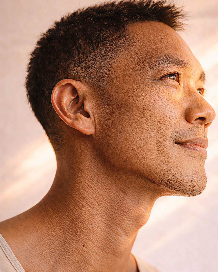 Side-profile portrait of a man with soft glowing light illuminating his face.