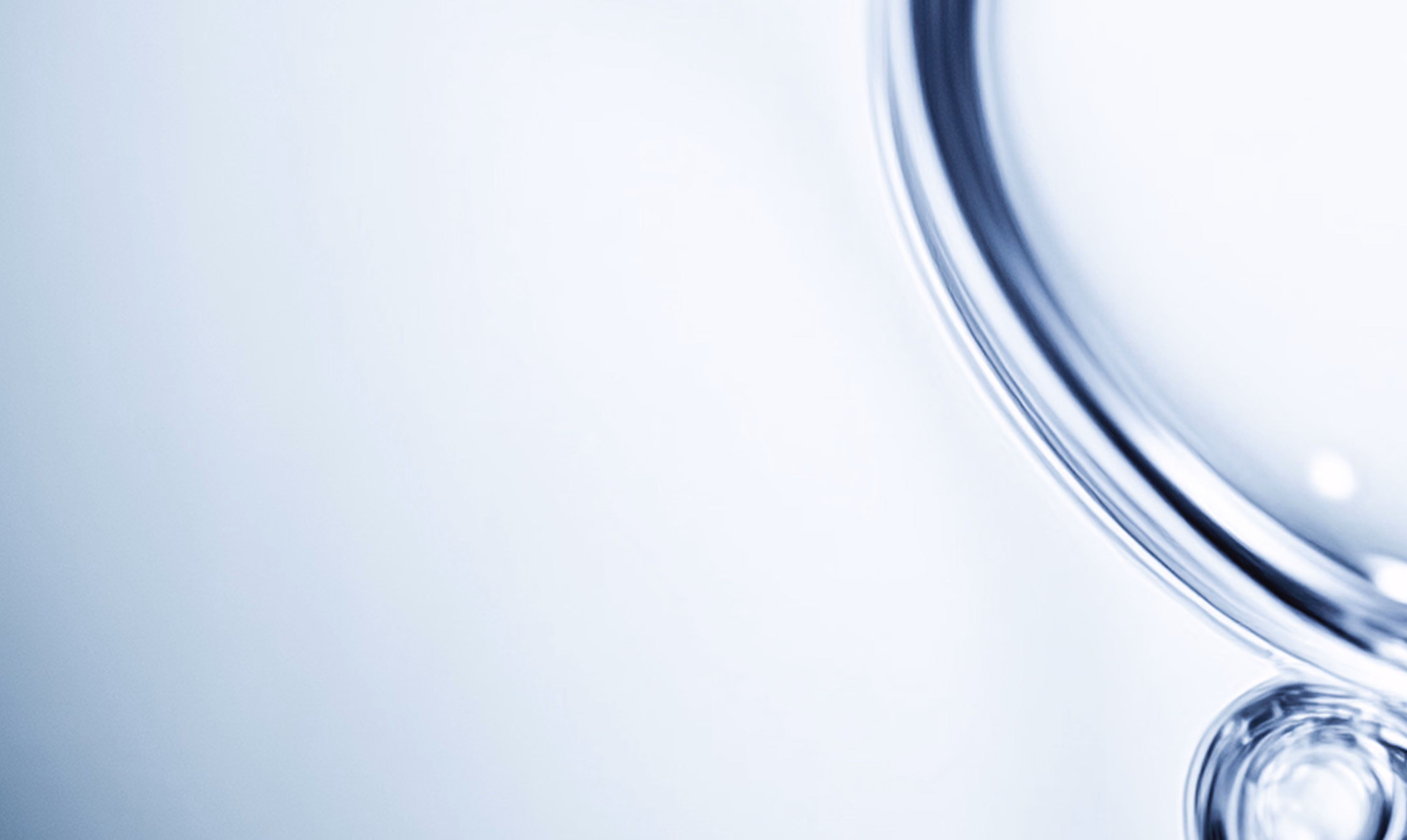 Close-up of clear, reflective liquid bubbles on a smooth light surface.