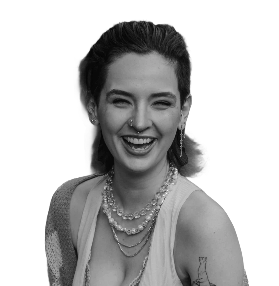 Black and white portrait of a smiling woman with curly hair, wearing a tank top and a necklace.
