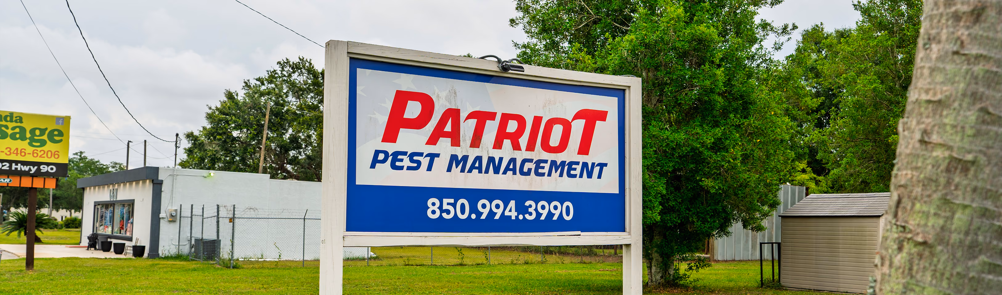 Outdoor sign for Patriot Pest Management with phone number 850.994.3990 on a grassy area.