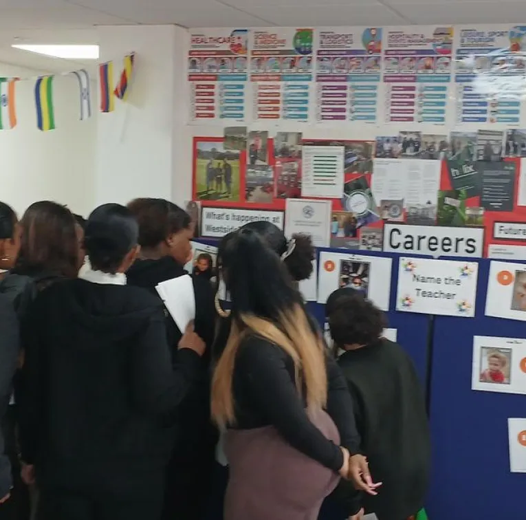 Group of people reading a career information board decorated with colorful posters and photos.