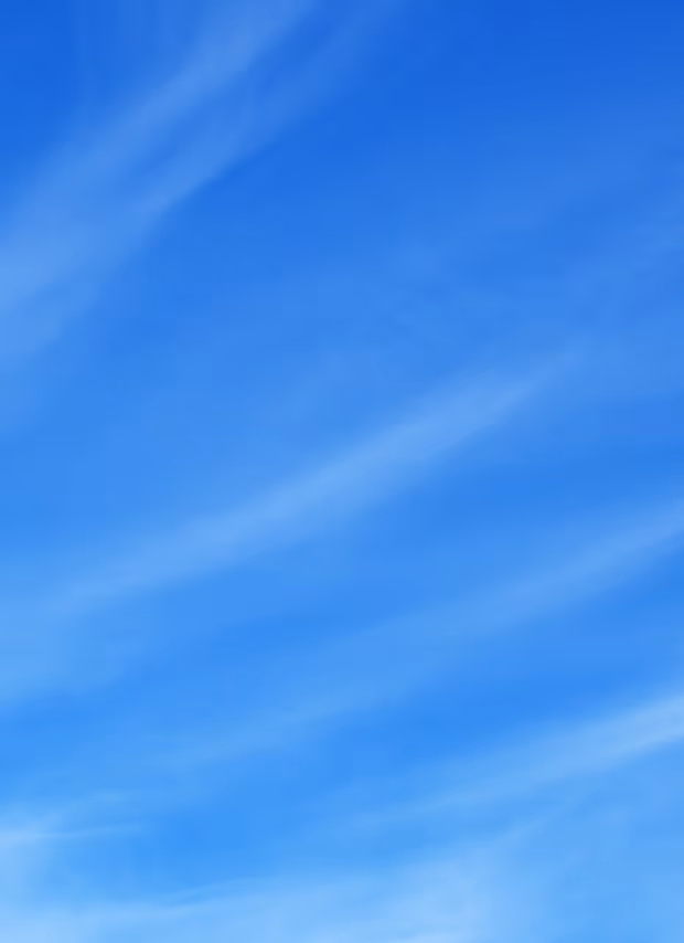 Bright blue sky with wispy white clouds scattered across.