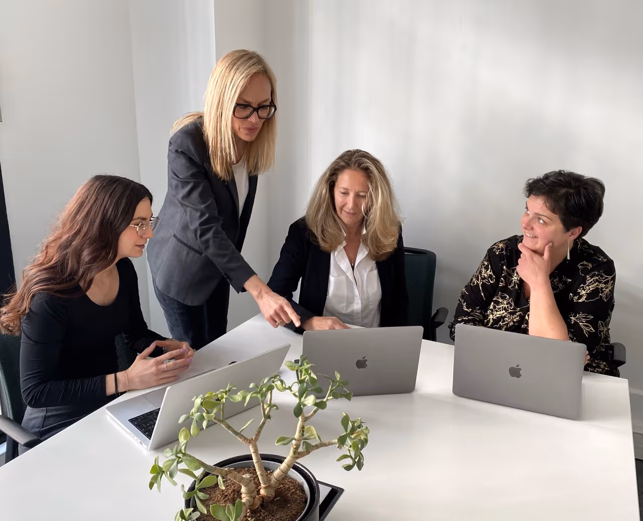 L'équipe Neovoxia en réunion de travail autour de deux ordinateurs portables sur une table blanche.