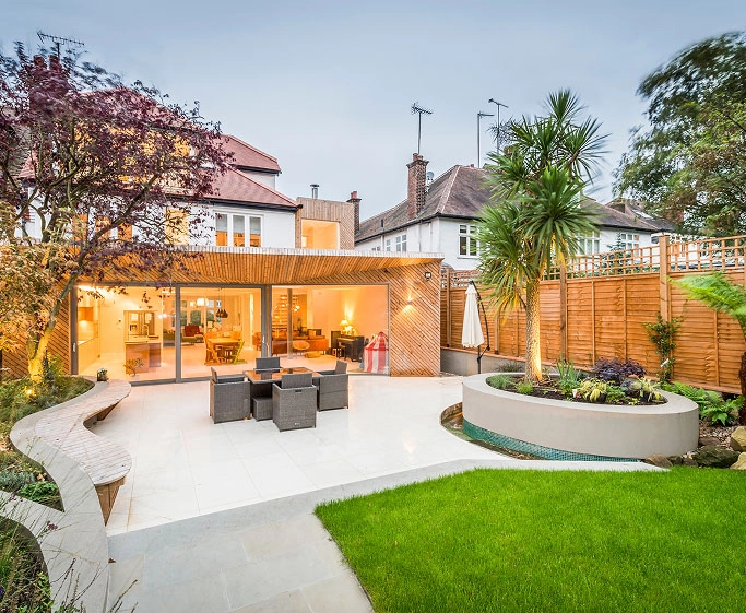 Modern backyard with patio, outdoor dining table, curved bench, planter, and house with large sliding doors.