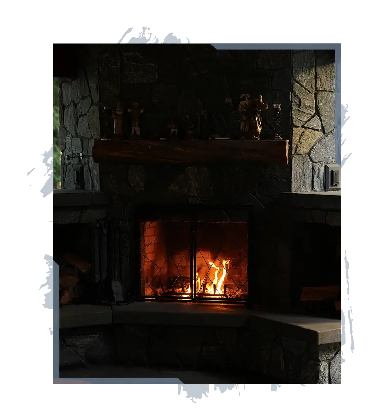 Stone fireplace with burning fire behind metal screen and wooden mantel with small figurines on top.