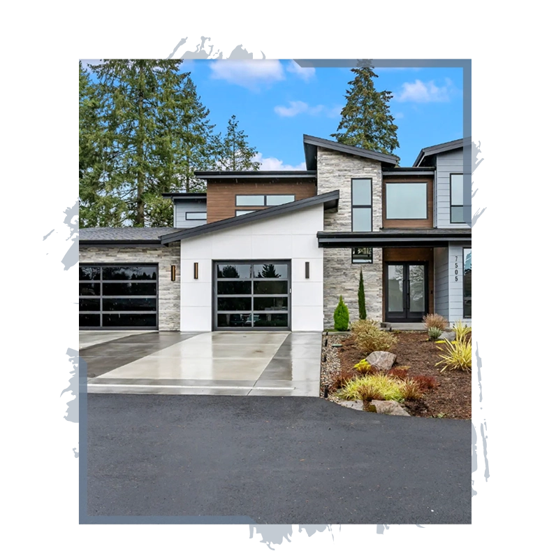 Modern two-story house with stone and wood siding, glass garage doors, and a landscaped front yard.