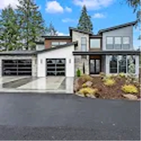 Modern two-story house with large windows, three garages, stone siding, and landscaped front yard.