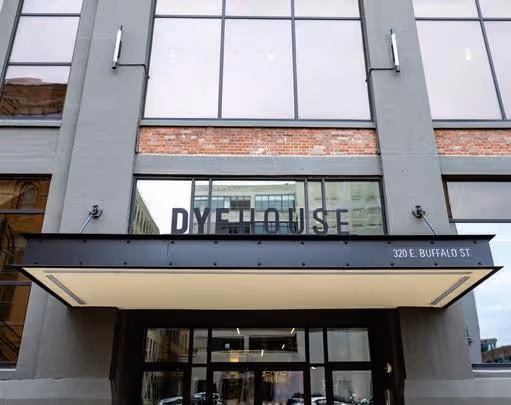 Entrance to a modern building with sign 'DYE HOUSE' and address '320 E. BUFFALO ST.'