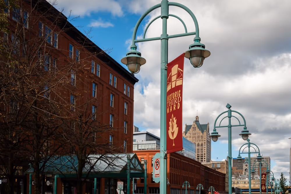 Street lamps with Historic Third Ward banners along a city street with red brick buildings and a cloudy sky.