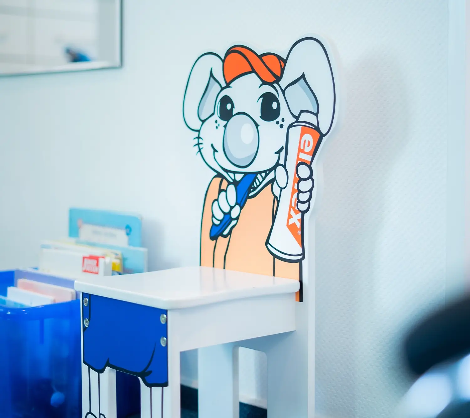 Kinderstuhl mit einer Cartoon-Maus, die eine Zahnbürste und Zahnpasta hält, in einem hellen Zimmer.