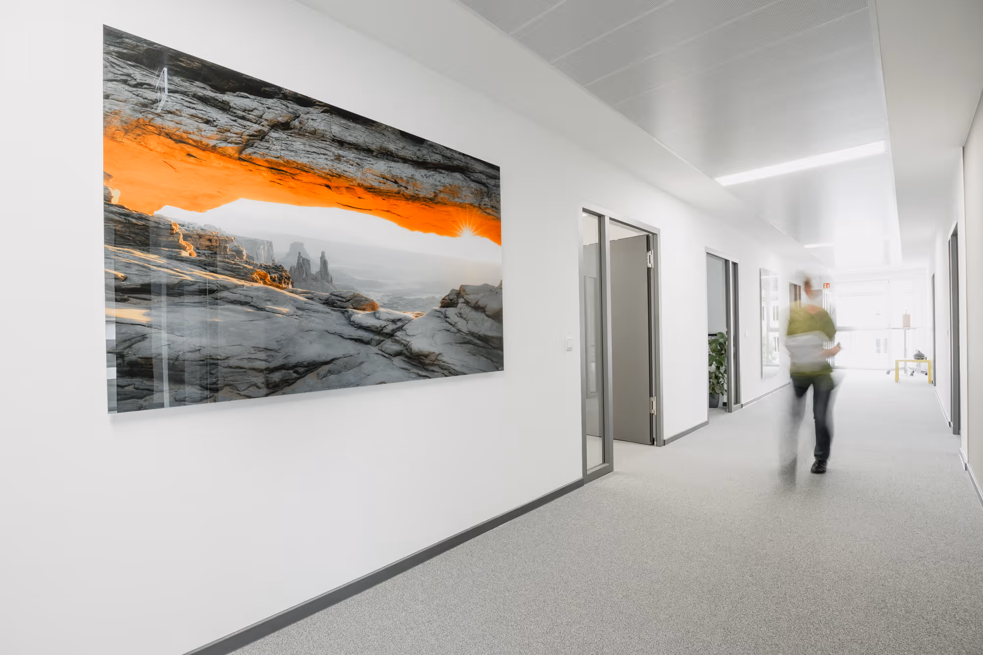 Flur mit weißem Boden, Türen rechts und Landschaftsfoto mit orangefarbener Felsformation links an der Wand.