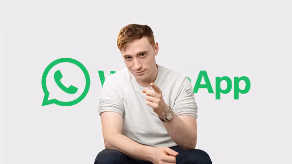 Junger Mann sitzt vor WhatsApp-Logo und zeigt nach vorne mit Finger.