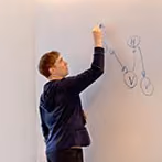 Mann schreibt und zeichnet auf ein Whiteboard im Büro oder Klassenzimmer.