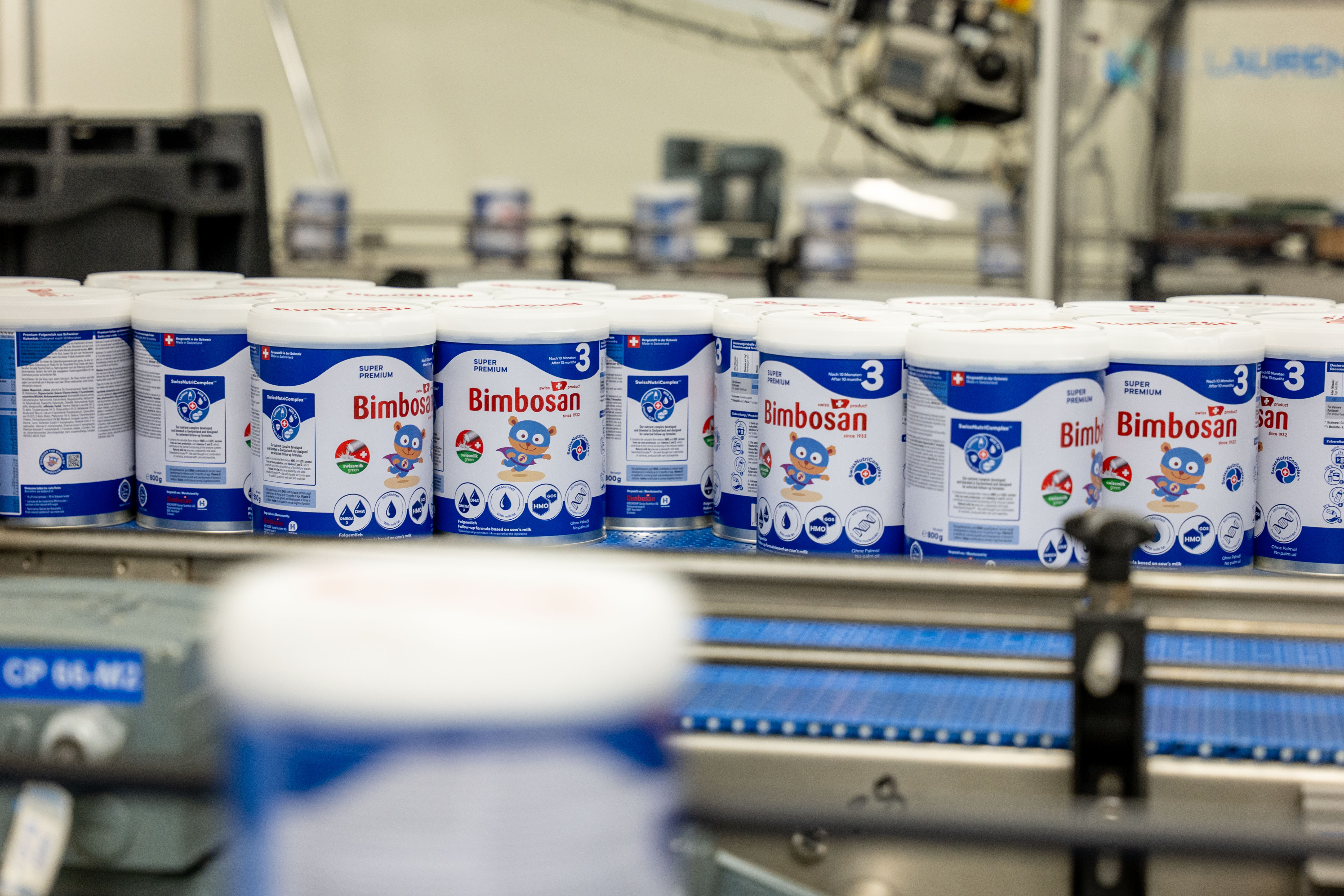 Barattoli di Bimbosan super premium nido 3 su un nastro trasportatore in produzione.