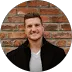 Adam Cole smiling, Detroit business IT client testimonial headshot with brick wall background