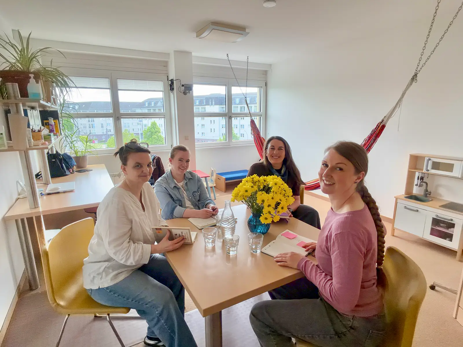 Elisabeth Warnke und ihr Team sitzen an einem Tisch mit gelben Blumen in einem hellen, modernen Raum.
