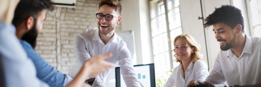 Business team laughing and collaborating around a conference table in a modern office workspace