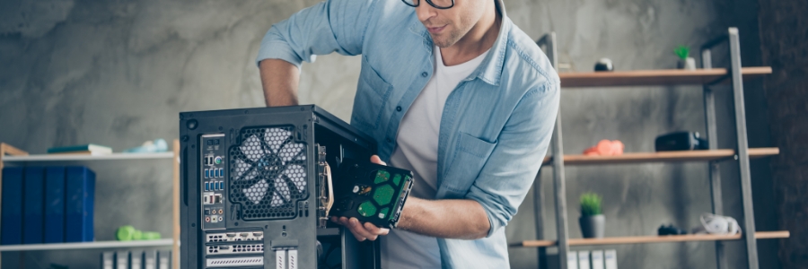 IT technician installing a hard drive into a desktop PC tower during a hardware upgrade or repair