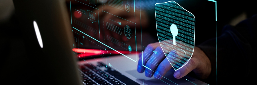Person typing on a laptop with a glowing cybersecurity shield and binary code hologram overlay