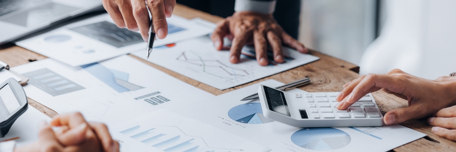 Business professionals reviewing financial charts and graphs on a wooden desk while using a calculator for data analysis
