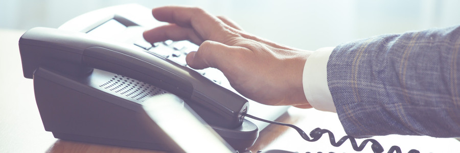 Business professional in suit dialing office desk phone for IT support services in Thousand Oaks CA