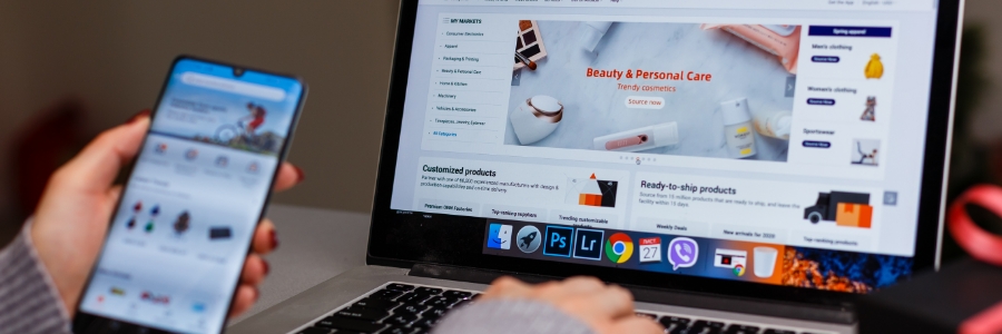 Person browsing an eCommerce website on a laptop while holding a smartphone, showing online retail product management