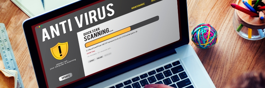 Laptop screen displaying antivirus software running a quick scan, with a person typing on the keyboard