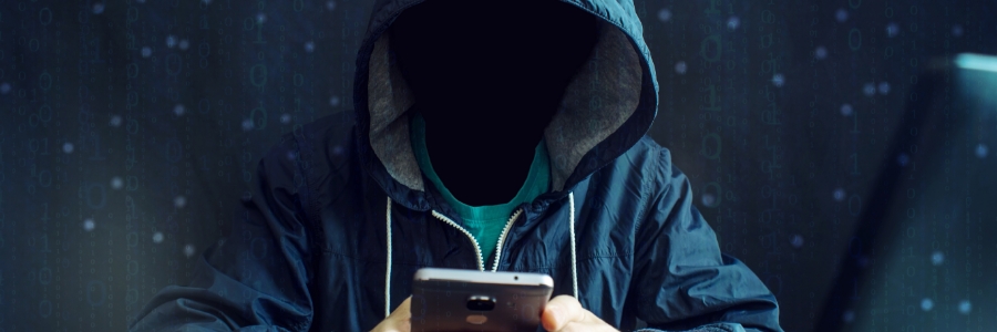 Hooded figure using smartphone in dark environment with binary code overlay, suggesting cybersecurity threat
