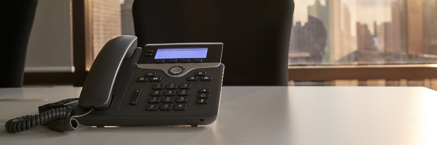 Cisco VoIP desk phone on office desk with city skyline background, representing business phone system solutions
