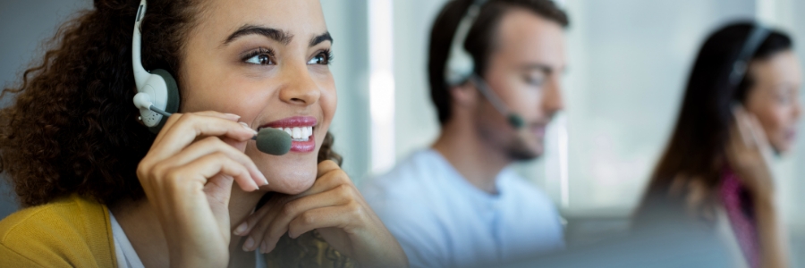 Smiling customer support representative wearing headset assists clients at IT help desk call center