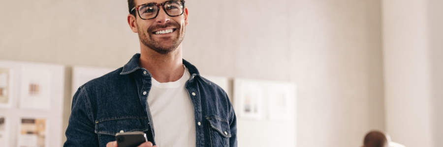 Smiling professional holding smartphone in modern office workplace